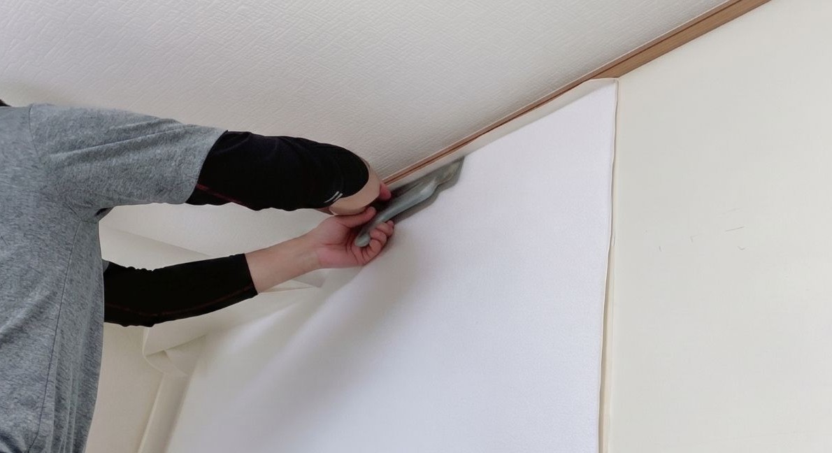 熟練の職人が壁紙（クロス）を丁寧に貼り合わせている作業風景